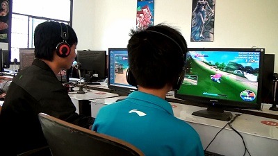 Students playing computer games at internet cafe.